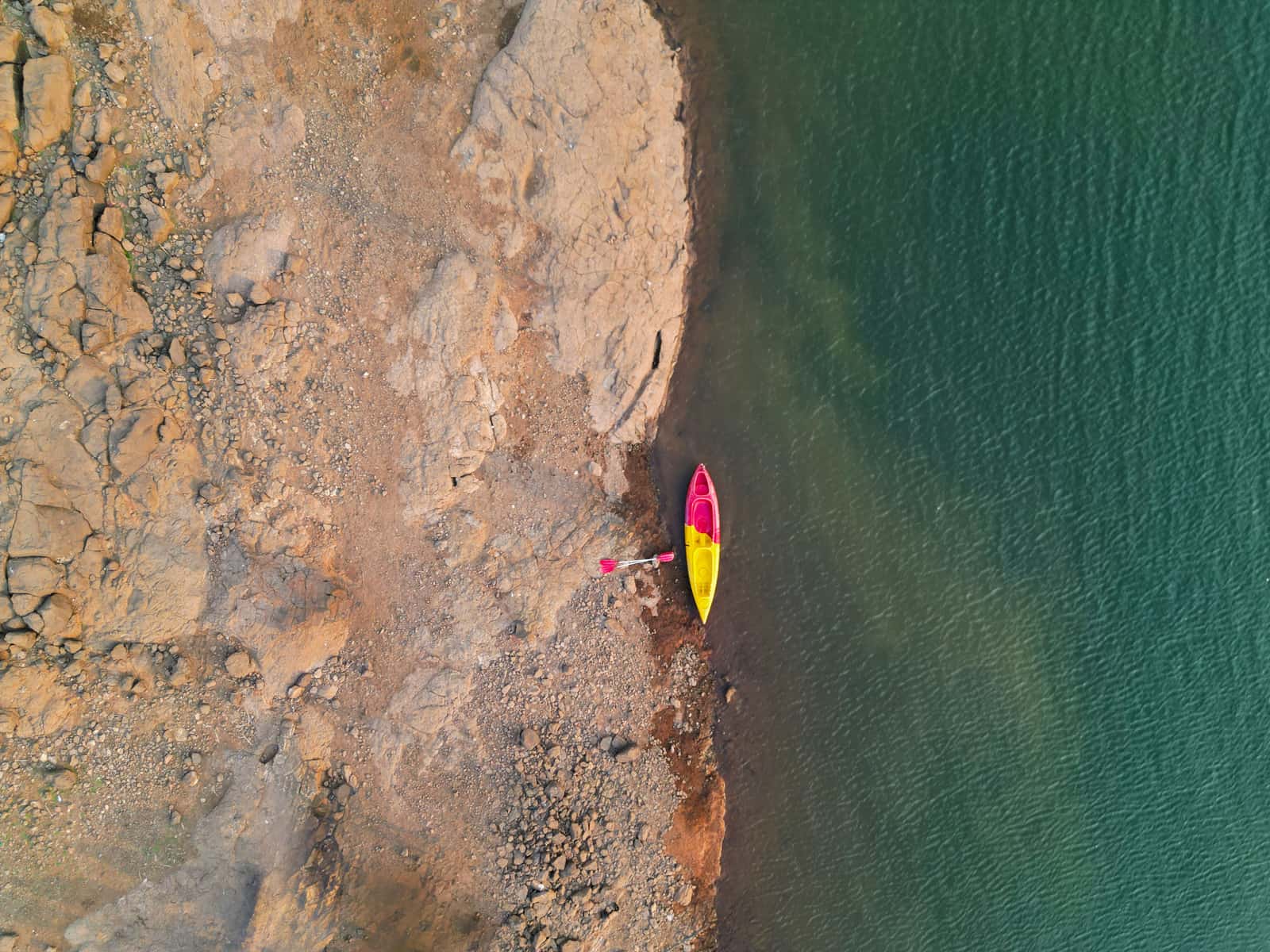 A single kayak drawn up on a rocky lake shore