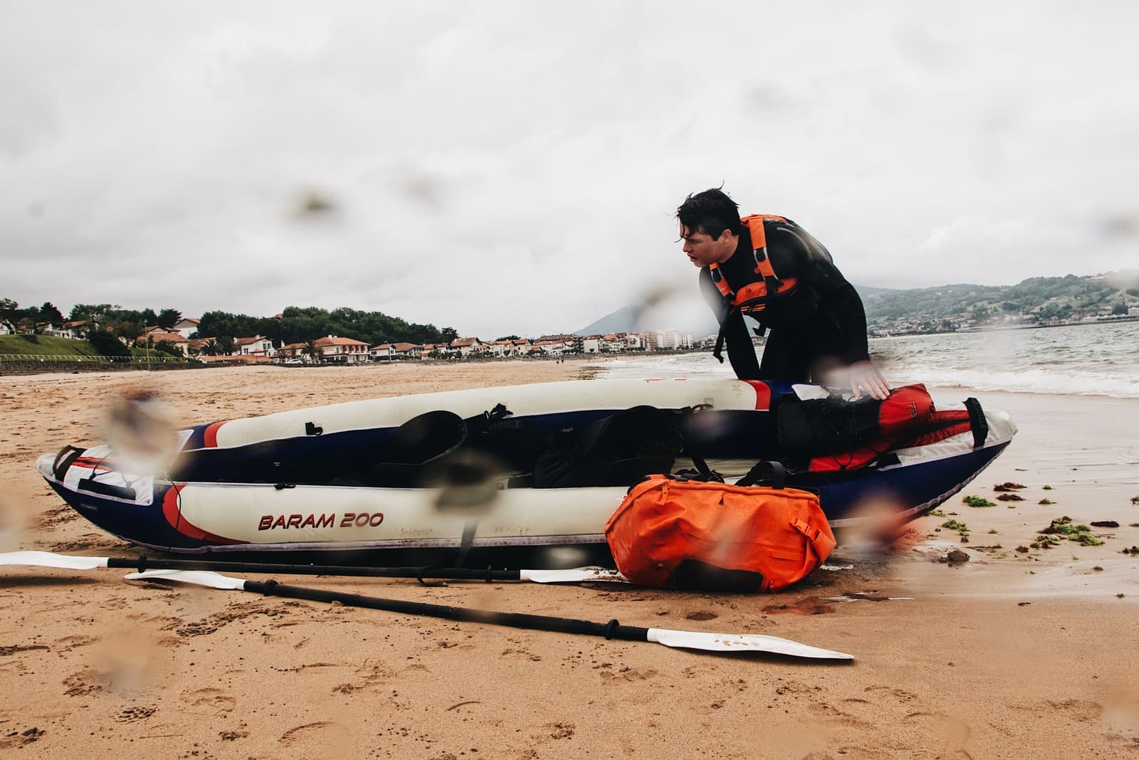 A paddler pushing an inflatable kayak out from the shore
