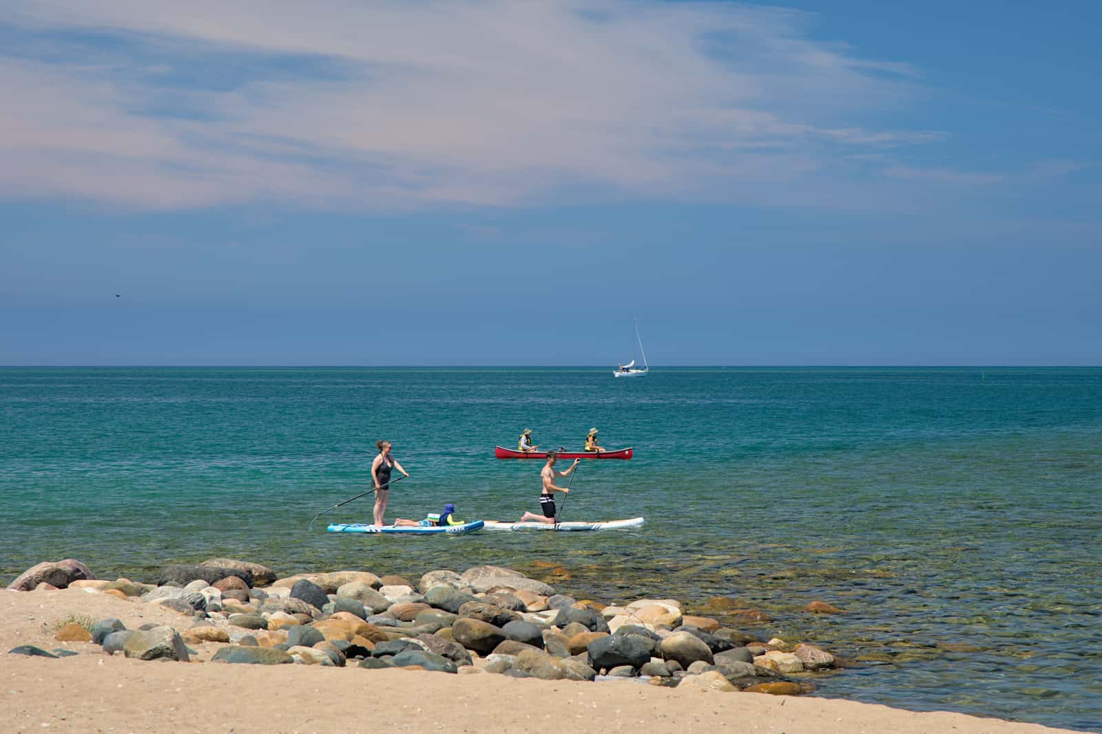 Paddle boarders and a kayak sharing a stretch of coastline