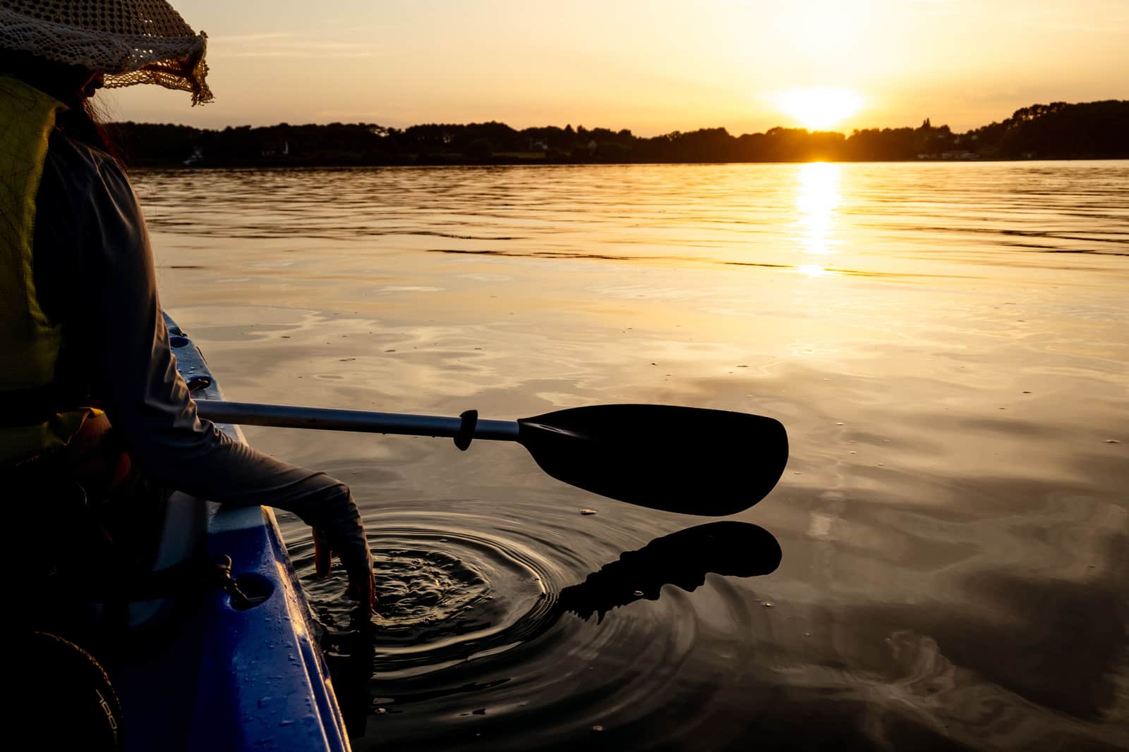 A paddler on flat water at the end of the day