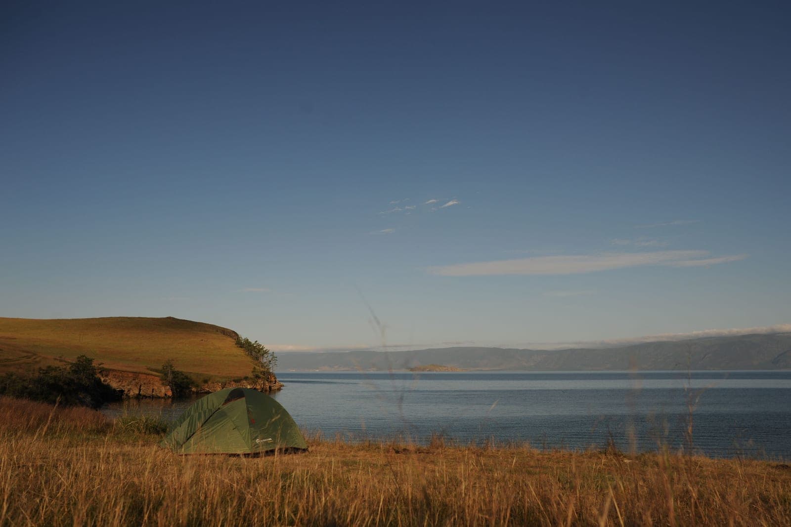 A tent pitched on a lakeshore at dusk