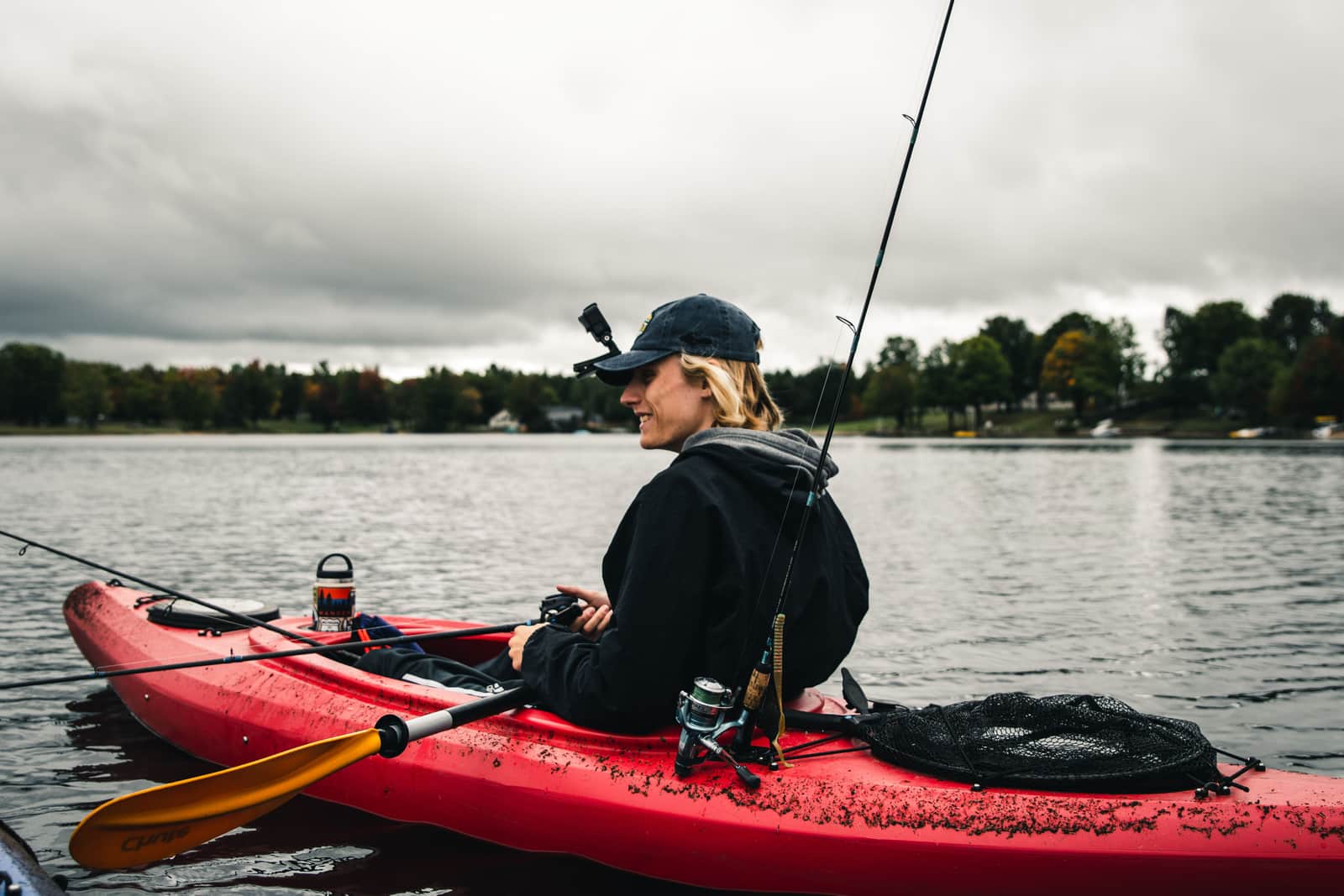 An angler casting a line from a small boat on flat water