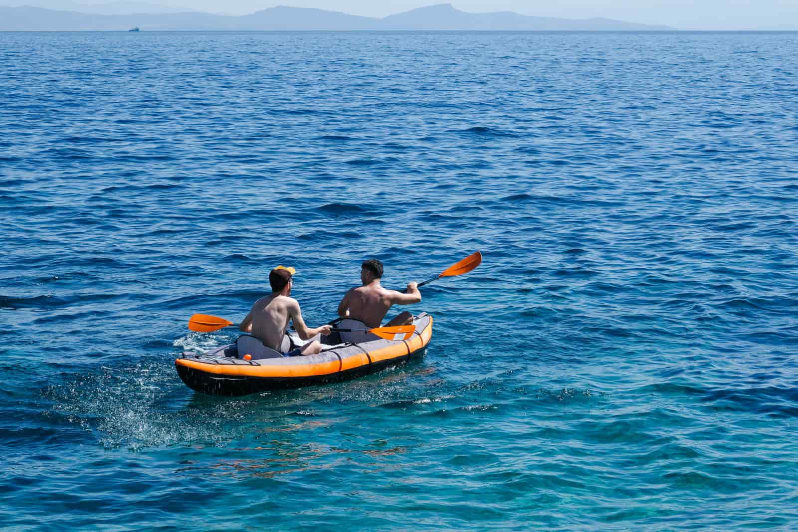 Two paddlers in a tandem inflatable kayak on open water