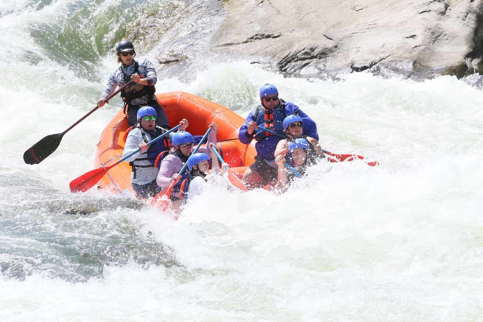 A raft running through whitewater rapids on a fast river