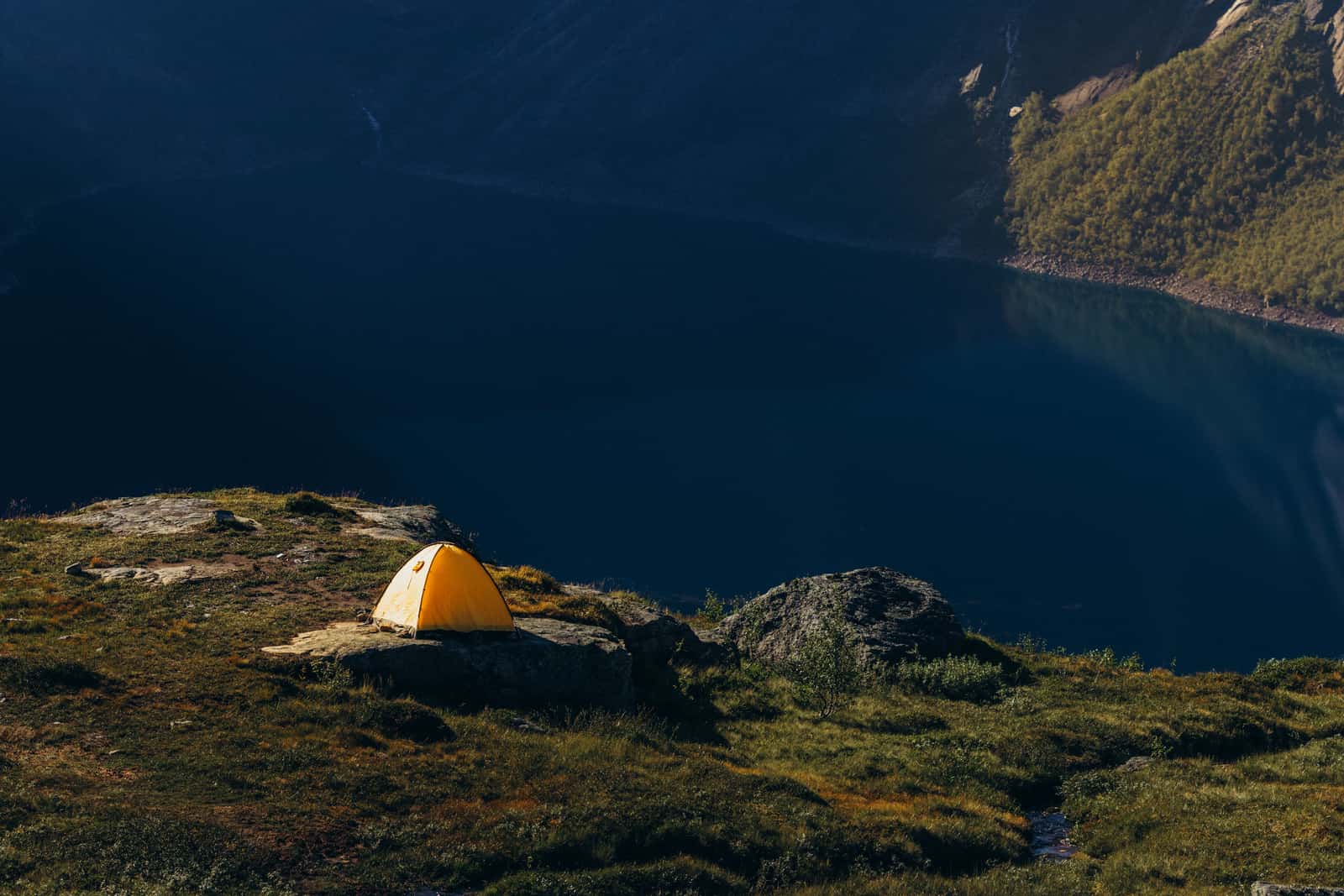 Camping and paddling gear laid out beside a lake at first light