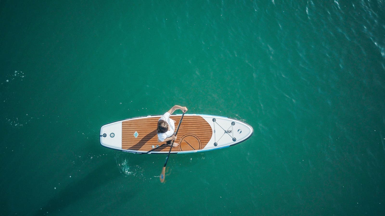 A person casting a fishing line from a stand up paddle board