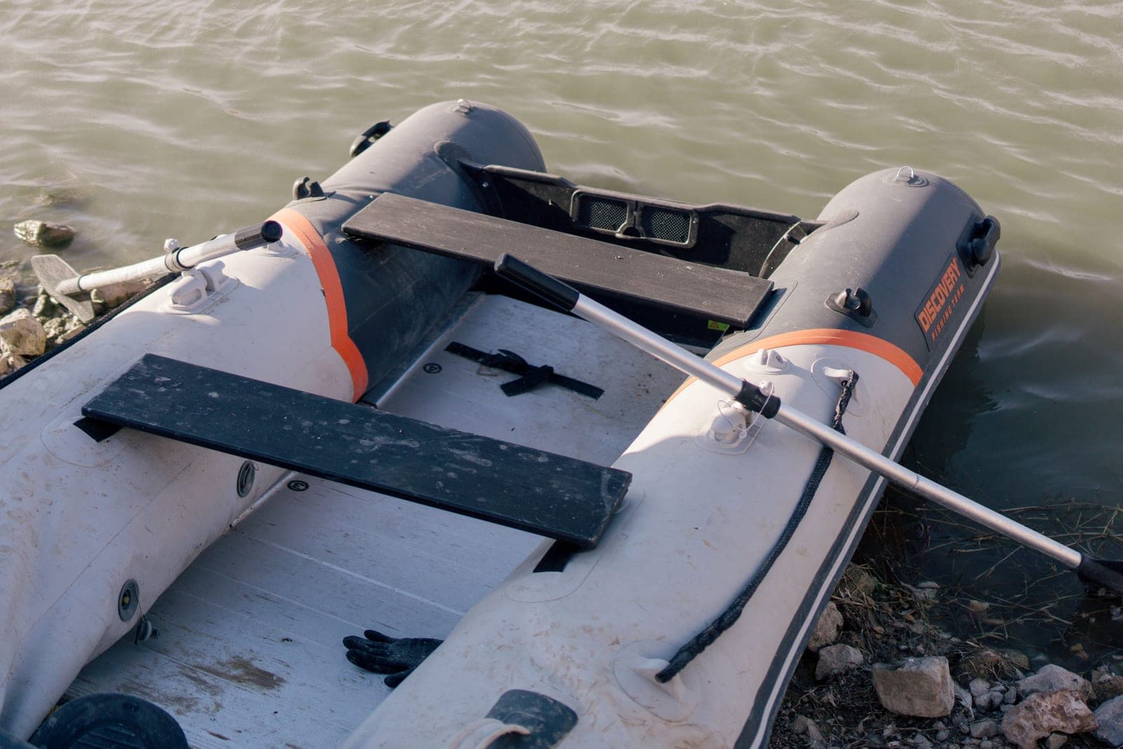 An inflatable paddle board resting at the edge of calm water
